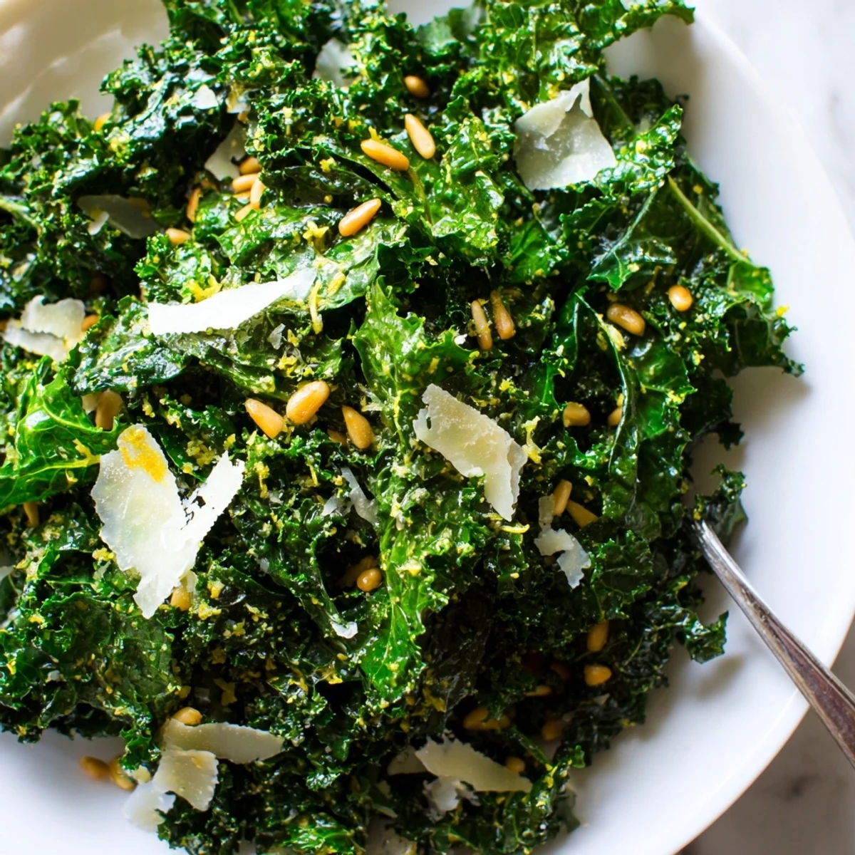 Crisp garlic lemon Parmesan kale salad in a wooden bowl with shaved cheese and toasted nuts