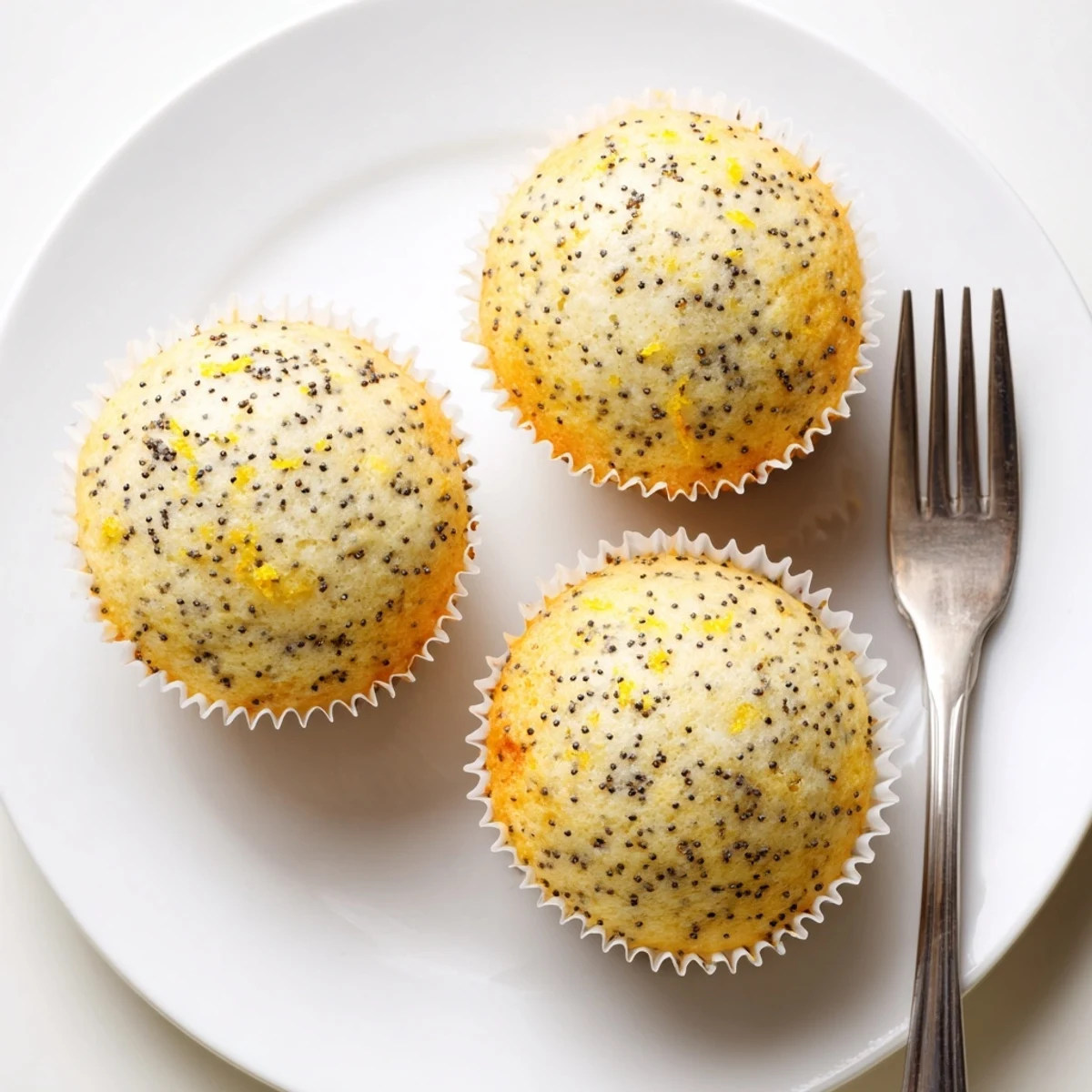Golden lemon poppy seed muffins with domed tops fresh from the oven on a wire cooling rack.