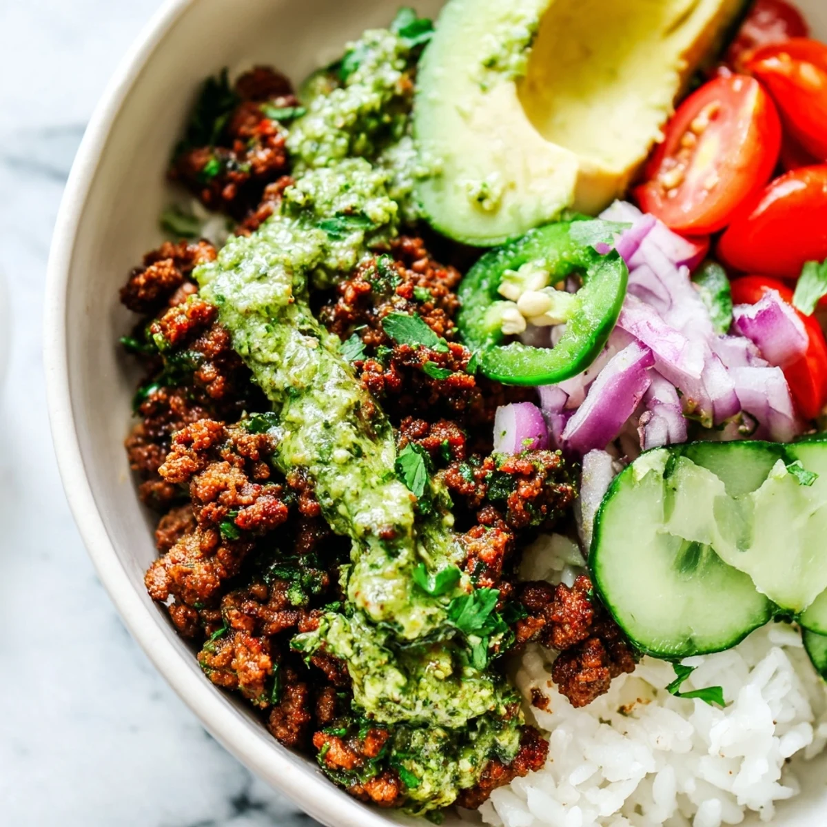 Colorful chimichurri ground beef bowls drizzled with herbaceous sauce over rice with fresh lime