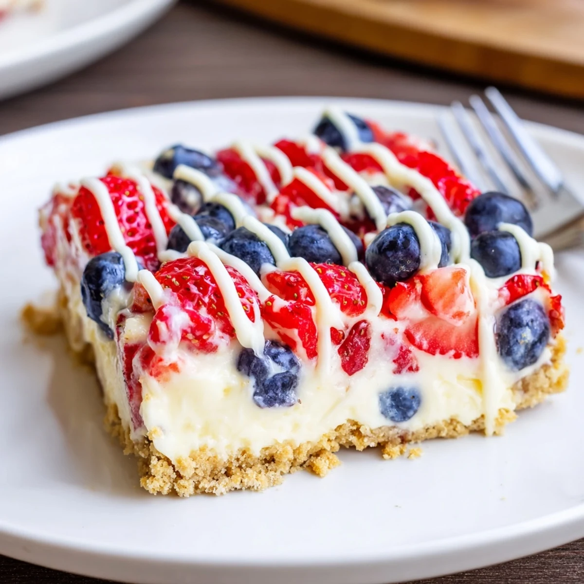 Patriotic Cheesecake Bars resting on parchment, buttery crust visible, berry-topped.