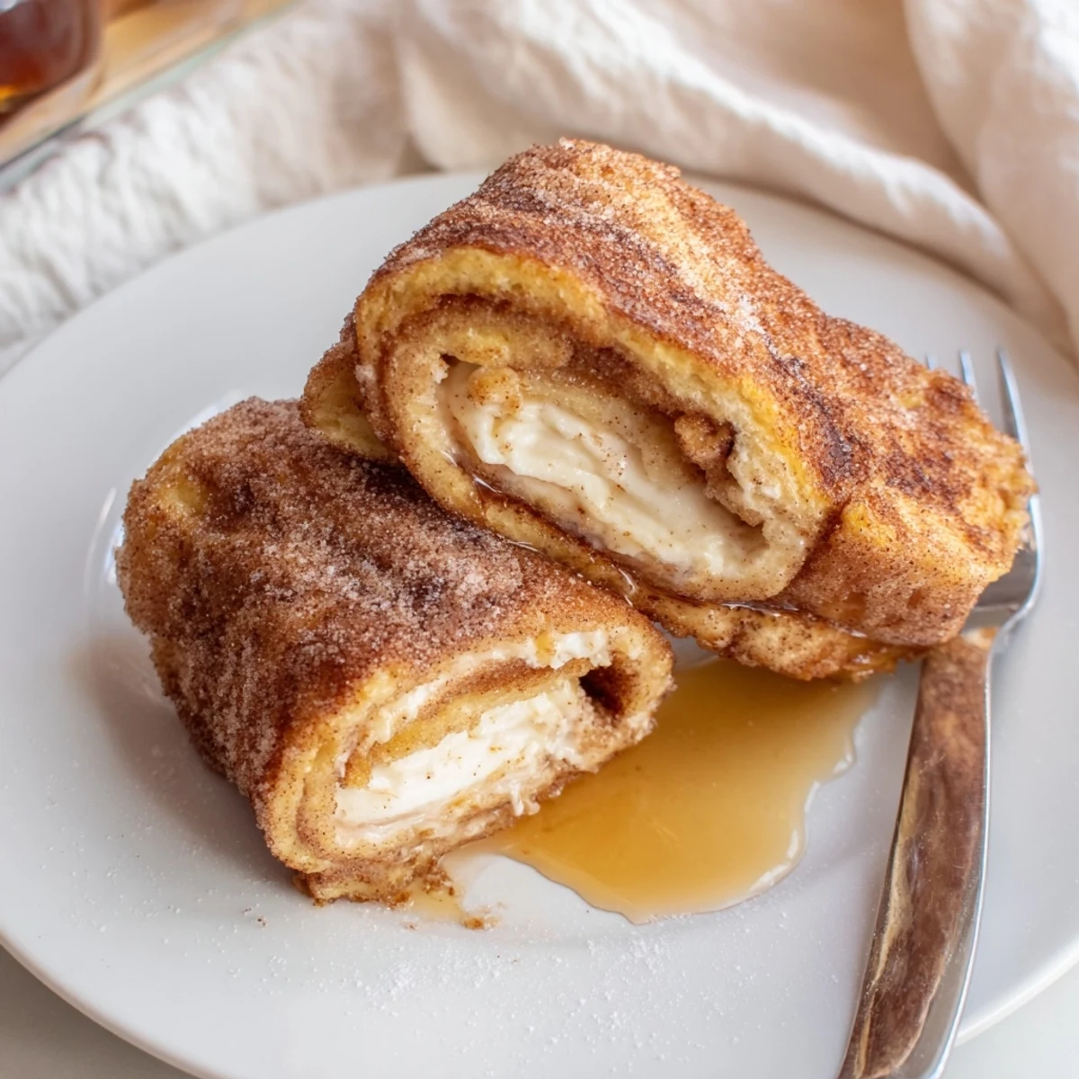 Warm Cinnamon Roll French Toast Roll Ups dusted with cinnamon-sugar, steaming