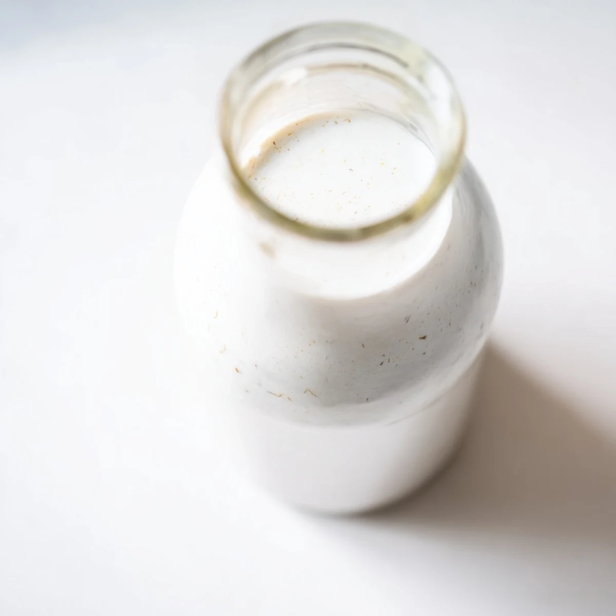 Fresh coconut milk being poured from blender into clear glass container