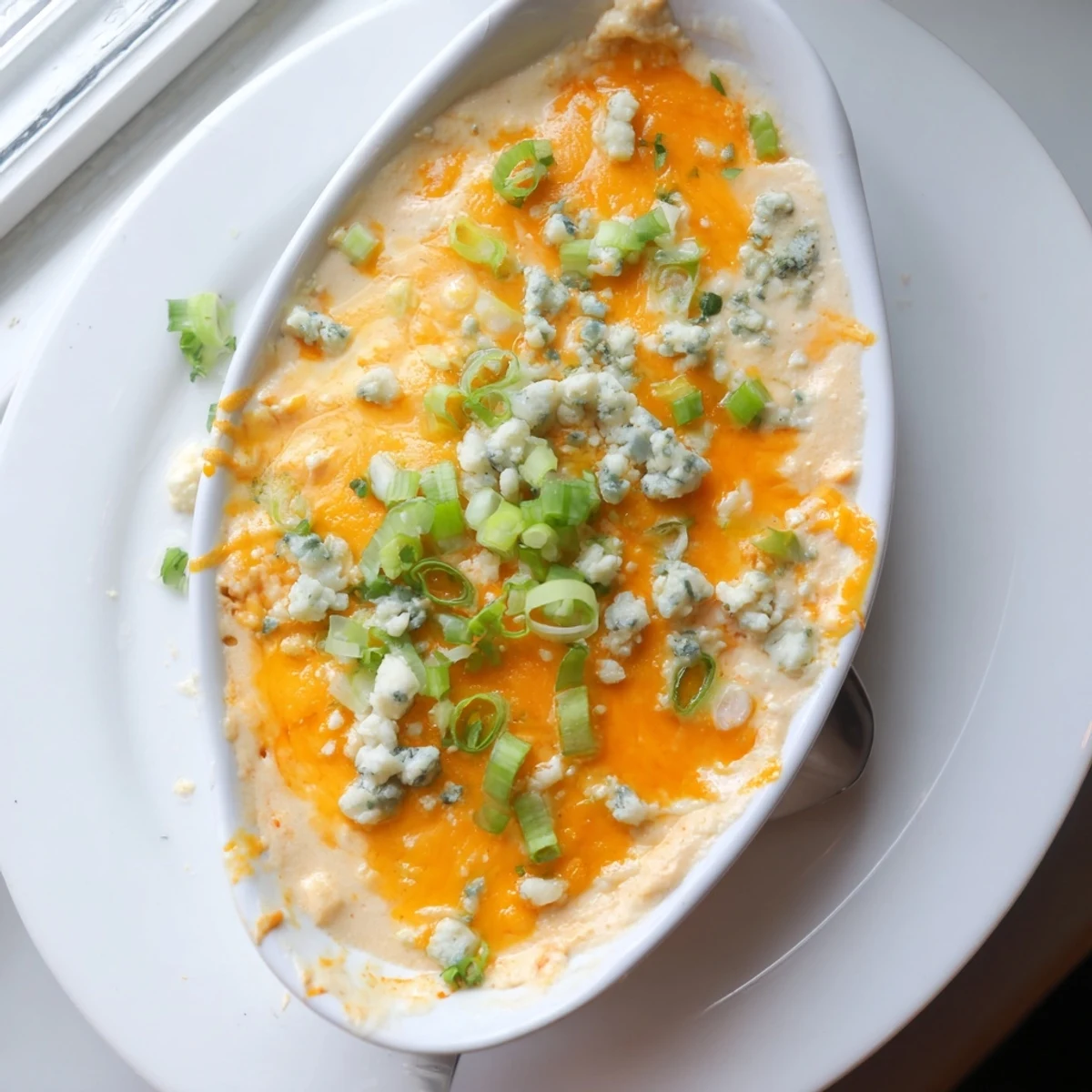 Creamy white bean buffalo dip appetizer sprinkled with fresh green onions and chopped parsley