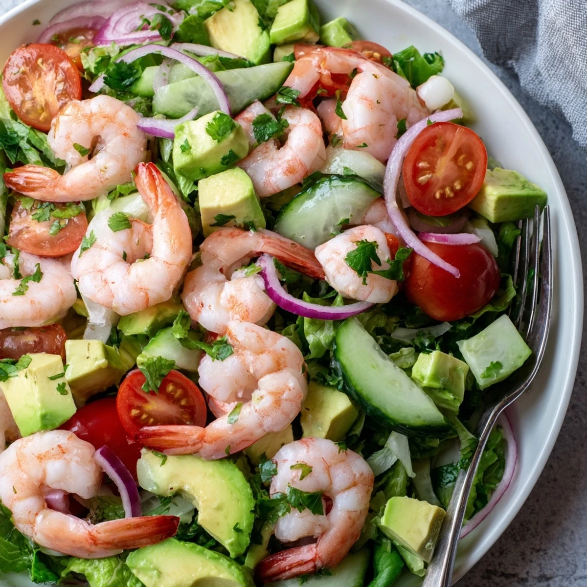 Fresh shrimp avocado salad recipe with pink shrimp, green avocado, and vibrant vegetables in a bowl