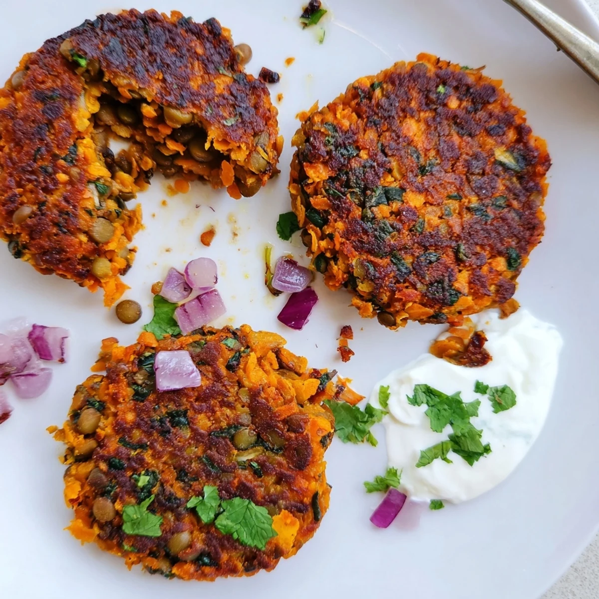 Warm, pan-fried Crispy Sweet Potato Lentil Patties on plate with avocado dip.
