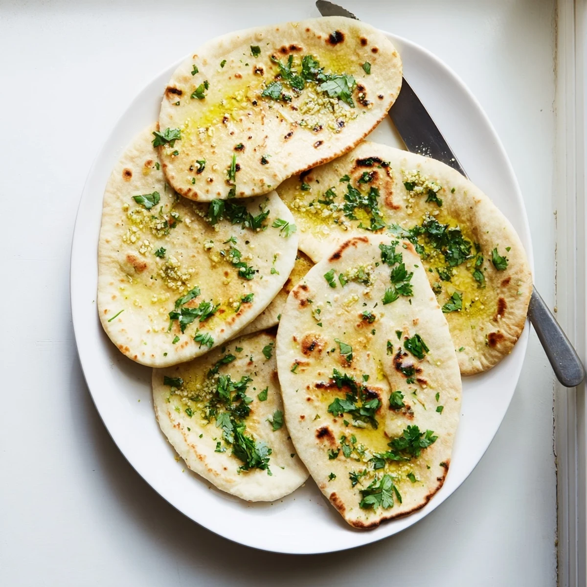 Golden brown sourdough discard soft naan brushed with melted butter and fresh herbs