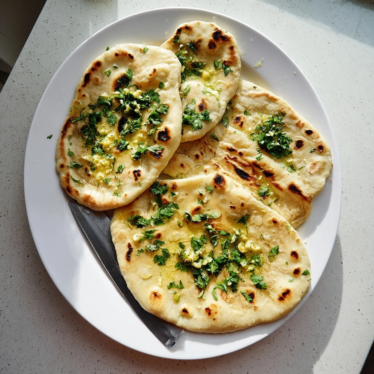 Pillowy homemade sourdough discard naan with charred bubbles, served warm alongside dishes