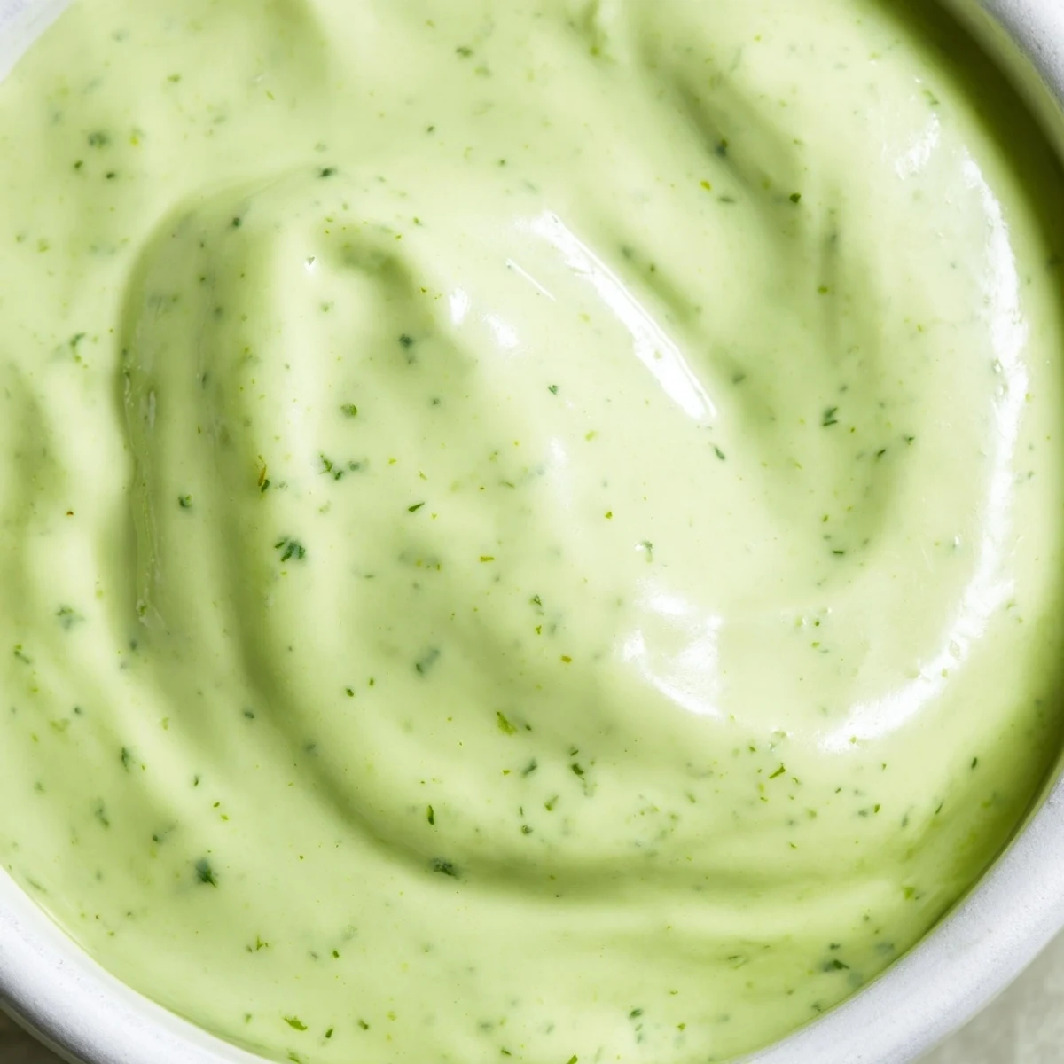 Smooth creamy cilantro lime sauce garnished with extra fresh cilantro leaves and lime wedge