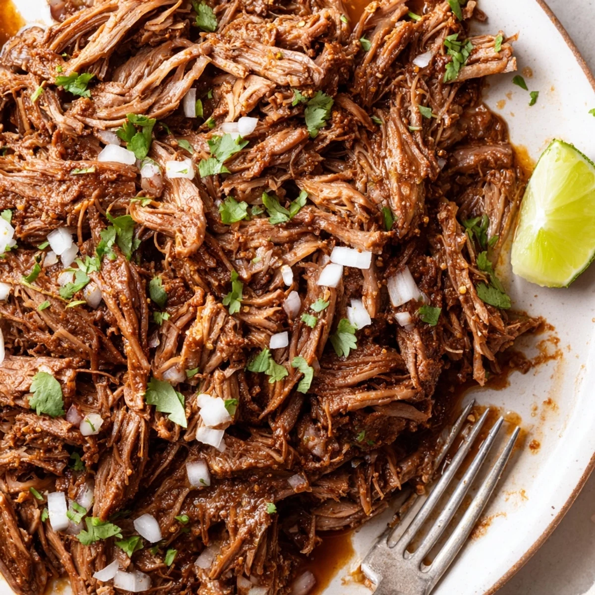 Heaping Slow Cooker Beef Barbacoa in bowl, juicy shreds with cilantro.