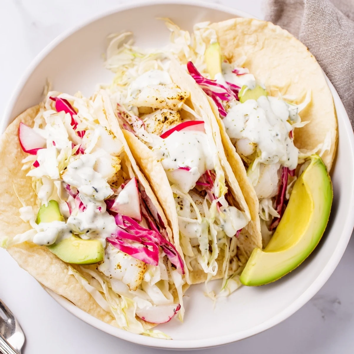 Baked Cod Fish Tacos with Creamy Cilantro Lime Sauce topped with crisp slaw