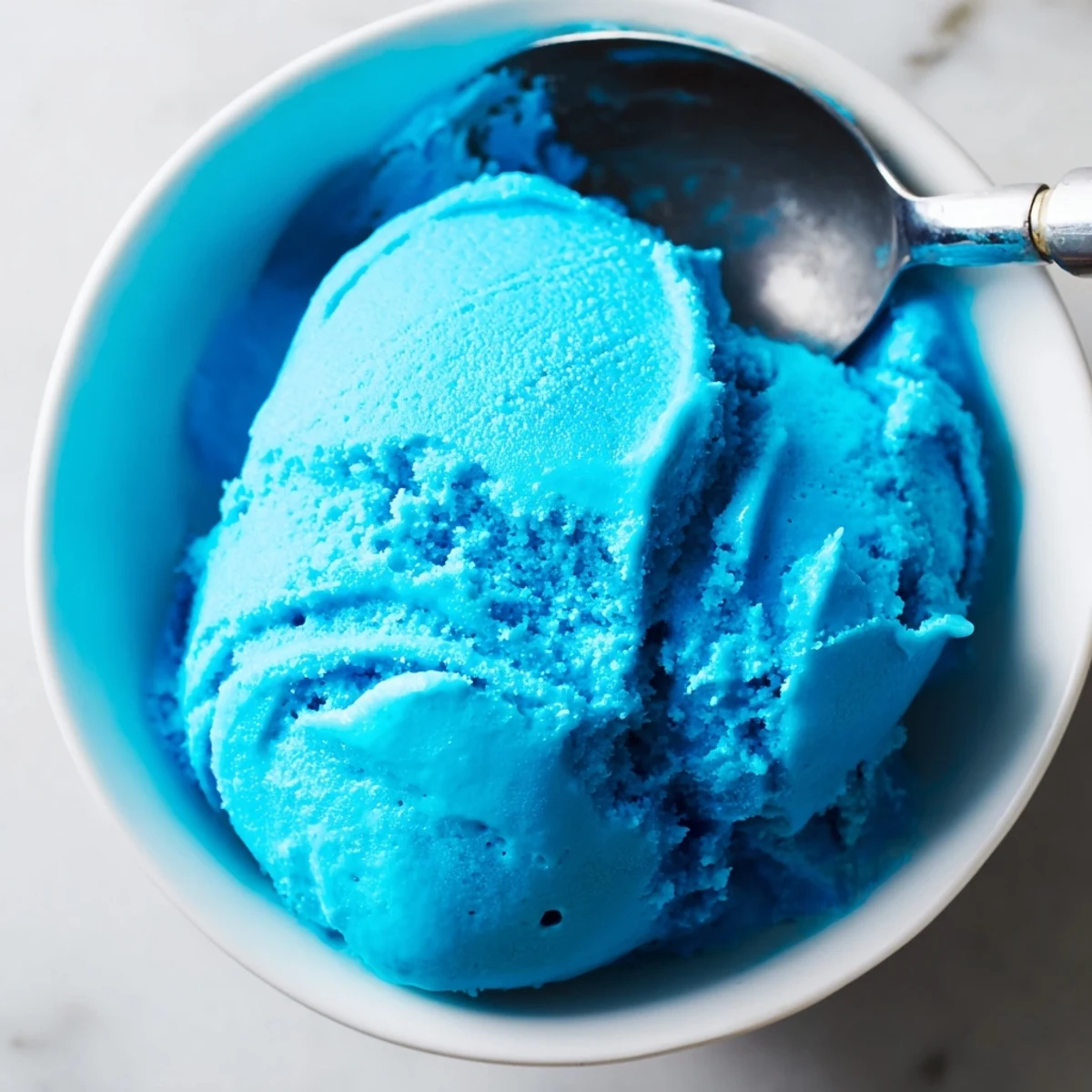 Vibrant blue moon ice cream served in a bowl with a silver spoon