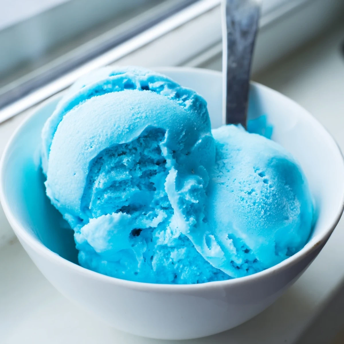 Homemade blue moon ice cream with a smooth bright blue swirl in a summer setting