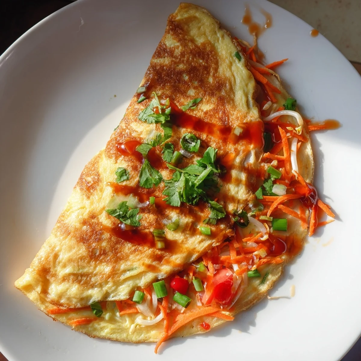 Golden Chinese omelette filled with crisp vegetables and fresh scallions on a white plate.