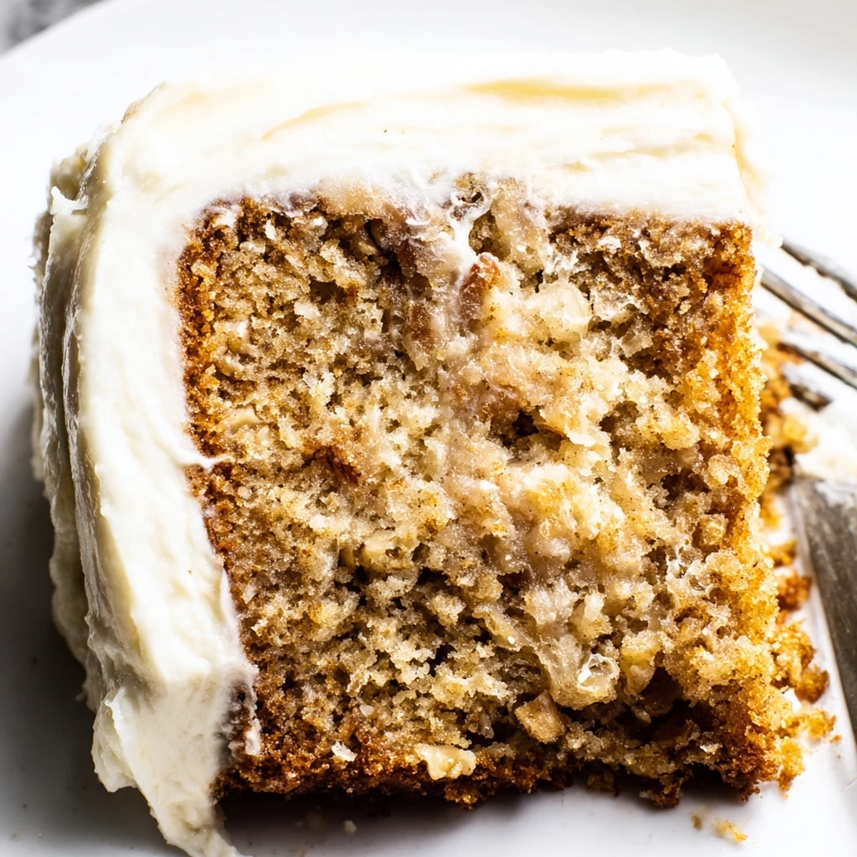 Moist brown butter banana cake layered with tangy cream cheese frosting served on ceramic dish