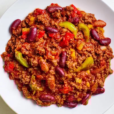 Hearty spicy beef chili with kidney beans simmering in a Dutch oven, steam rising with bold spices.