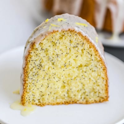 The golden-brown Lemon Poppy Seed Bundt Cake is sliced to reveal its fluffy interior, garnished with lemon zest and ready to serve with afternoon tea.