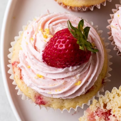 Golden strawberry lemonade cupcakes piled high with swirled pink buttercream and bright lemon zest